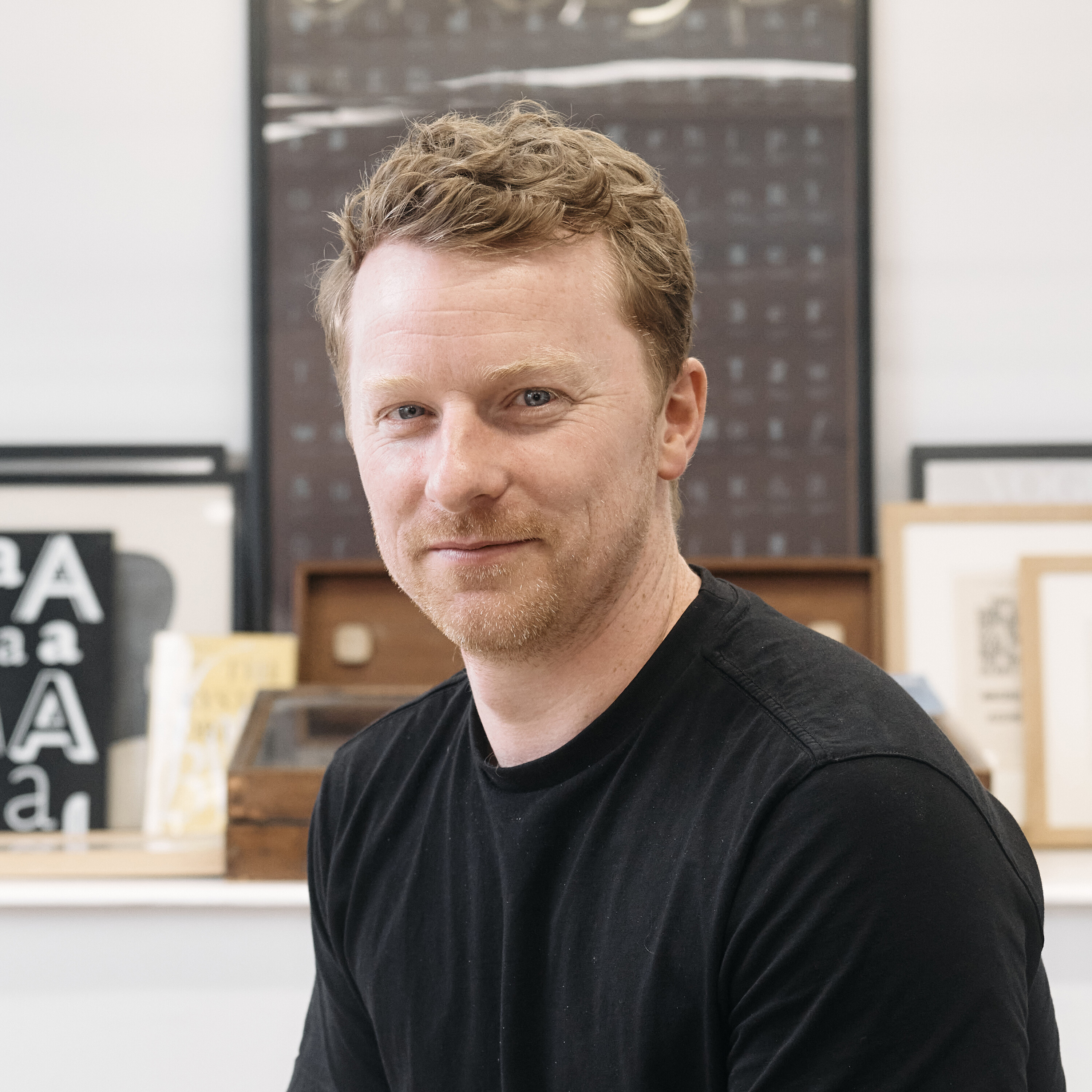 Tom Foley headshot. Wearing a black shirt in a bright office. 